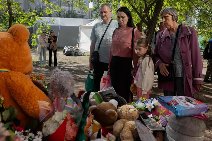 RESIDENTS stand in front of a makeshift memorial near a partially destroyed building in Kyiv.&mdash;AFP