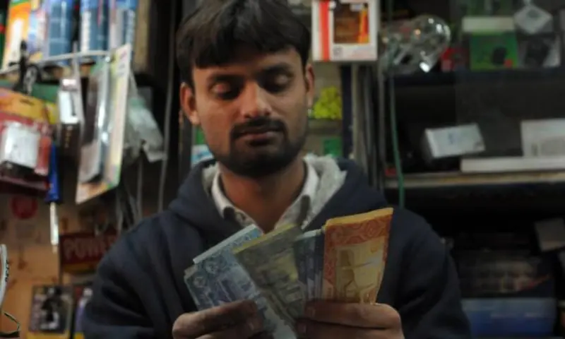 A shopkeeper counts money at his shop in Islamabad. &mdash; AFP/File