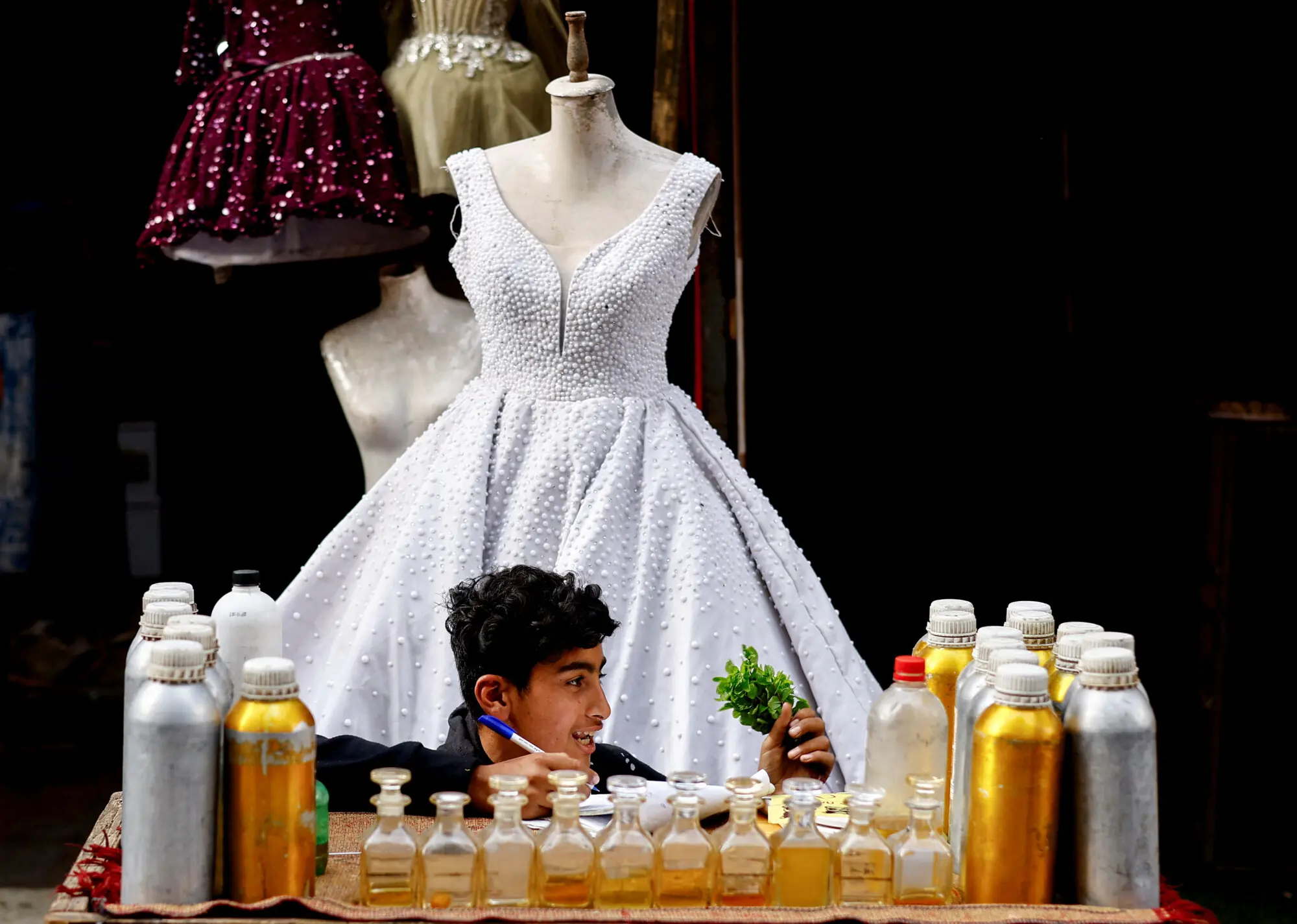 A young boy sells perfumes outside a shop selling wedding dresses in Gaza
