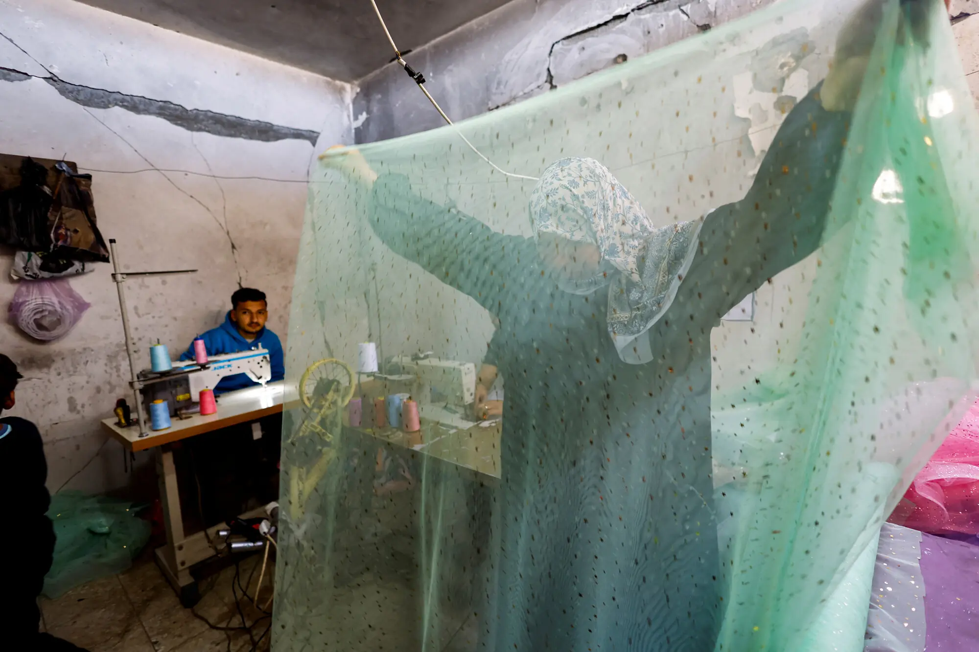 A woman inspects cloth at a workshop refurbishing dresses in Gaza