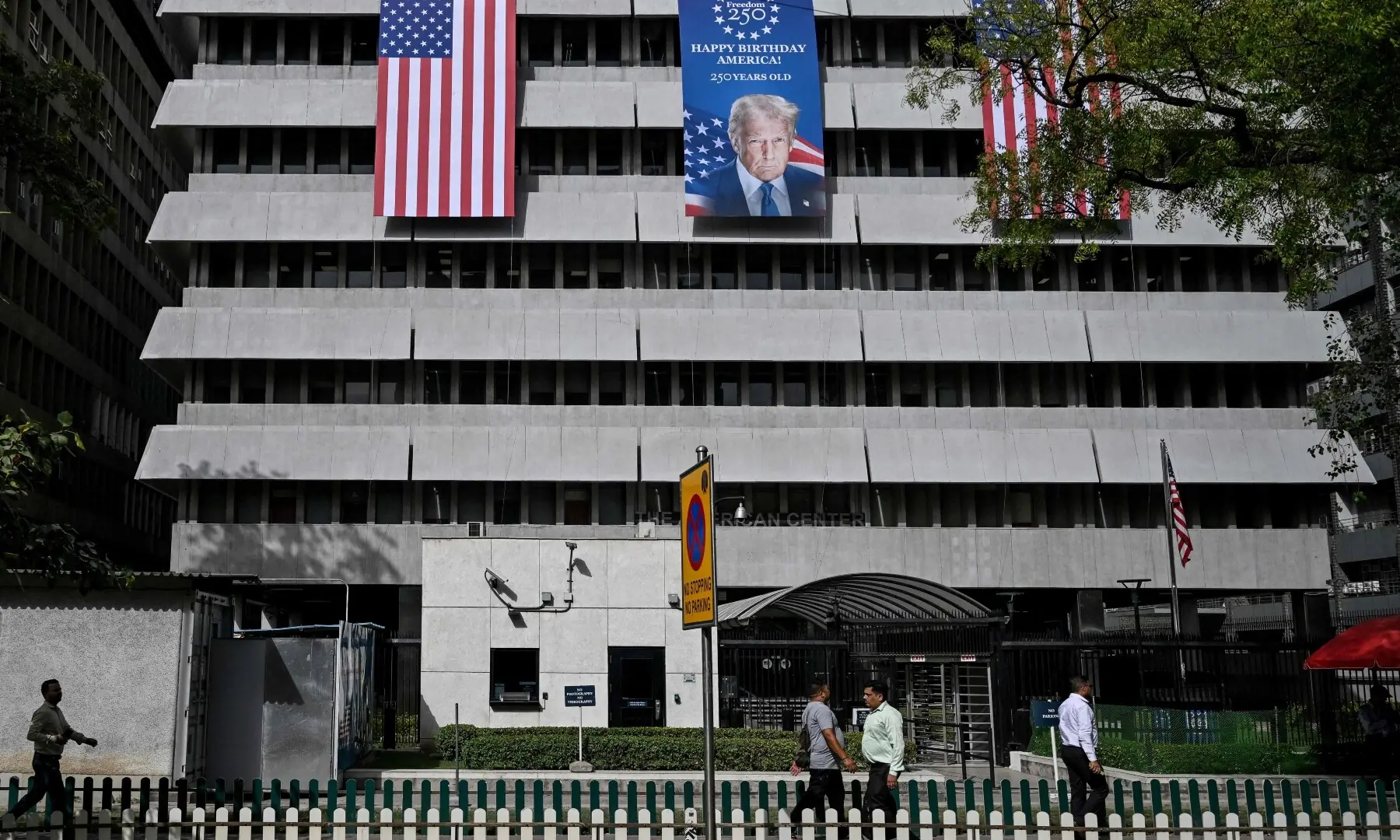 Pedestrians walk past a poster featuring US President Donald Trump outside the American Center in New Delhi on May 21, 2026 marking the 250th anniversary of American independence. —AFP