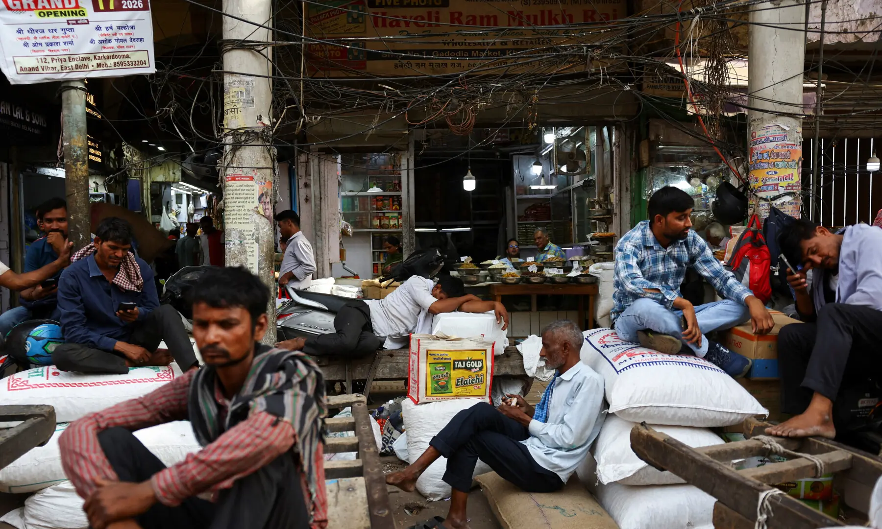 A labourer sleeps on a handcart while others rest on gunny bags in a market on a hot summer day in Old Delhi, India on May 22, 2026. &mdash; Reuters