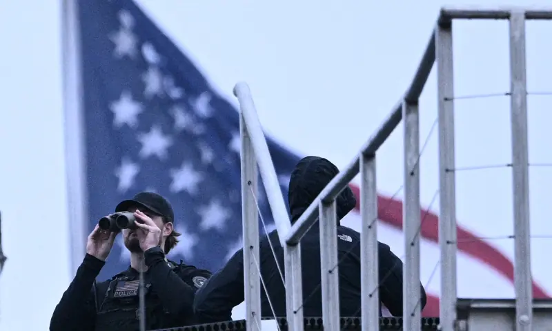 A police officer uses binoculars on the roof of a building at the White House in Washington, DC, after shots were reportedly fired on May 23, 2026. — AFP A police officer uses binoculars on the roof of a building at the White House in Washington, DC, after shots were reportedly fired on May 23, 2026. — AFP