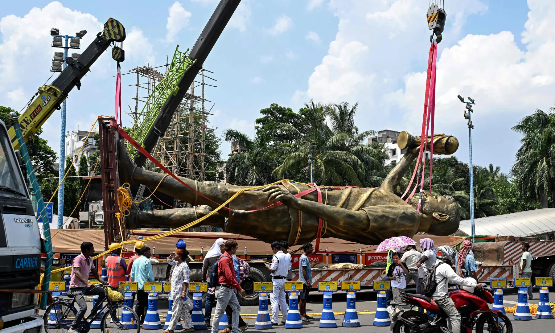 Pedestrians watch as workers remove a statue of Argentine football player Lionel Messi for its re-installation to a safer place in Kolkata on June 1, 2026. &mdash; AFP