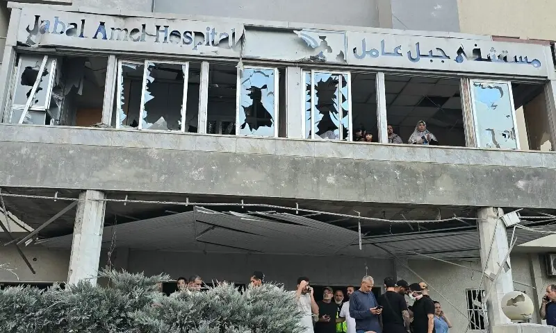 People gather while others look through damaged hospital windows at the site of an Israeli strike that hit near the hospital in the southern Lebanese city of Tyre on June 1. &mdash; AFP