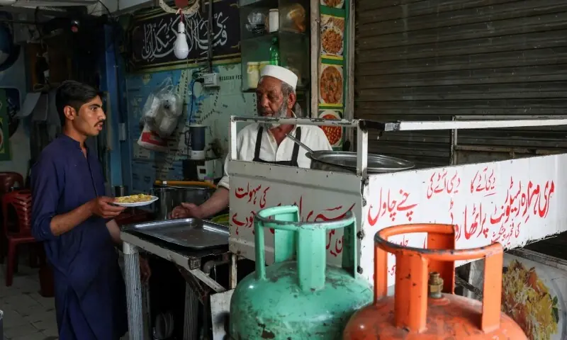 Workers serve food prepared on a gas cylinder stove at a tea shop, during power outages in Islamabad on April 23, 2026. &mdash; Reuters