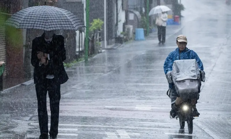 People commute in heavy rain brought by severe tropical storm Jangmi in Tokyo on June 3, 2026. &mdash; AFP