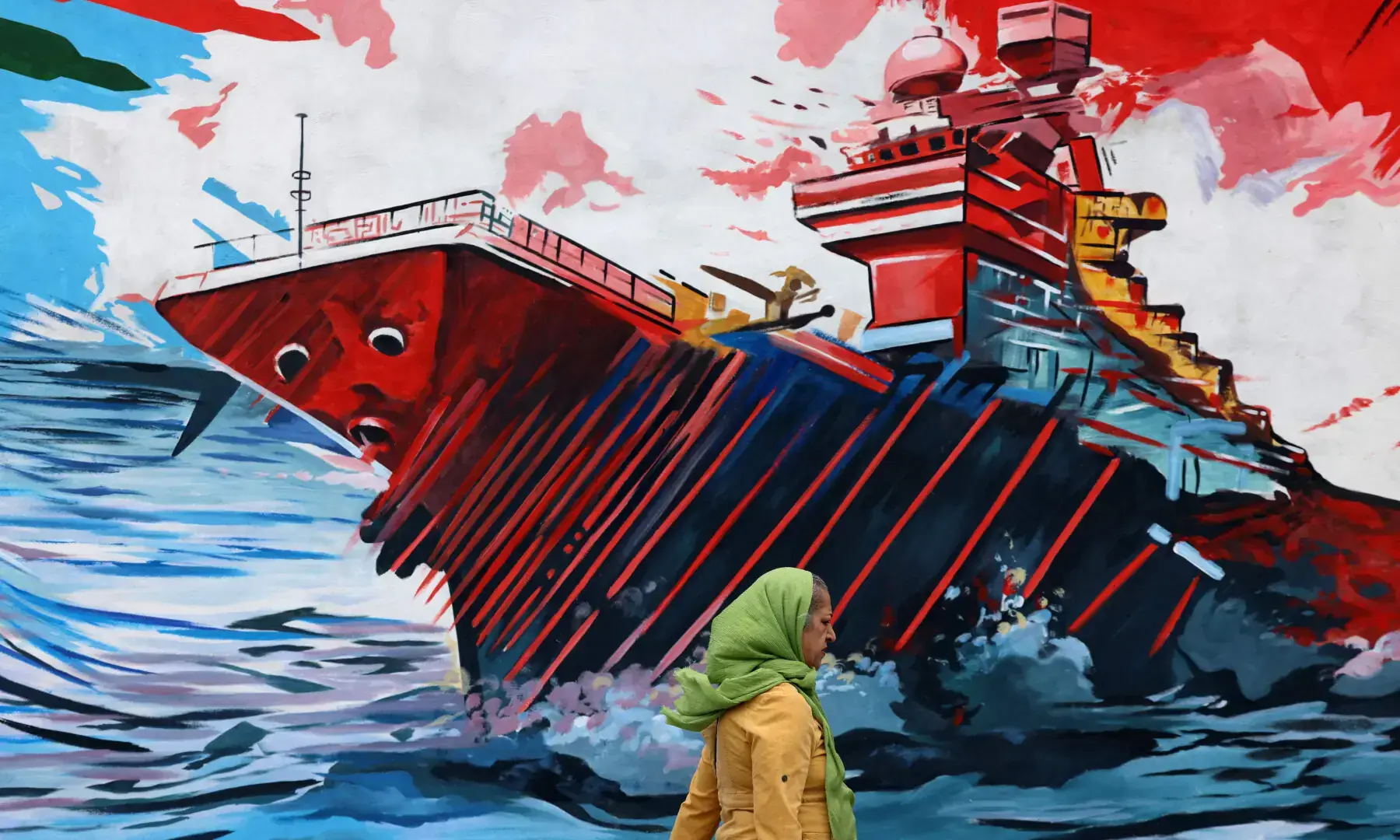 This photo taken on April 8, 2026 shows a woman walking past an anti-USA and anti-Israel mural, in Tehran. &mdash; AFP/File