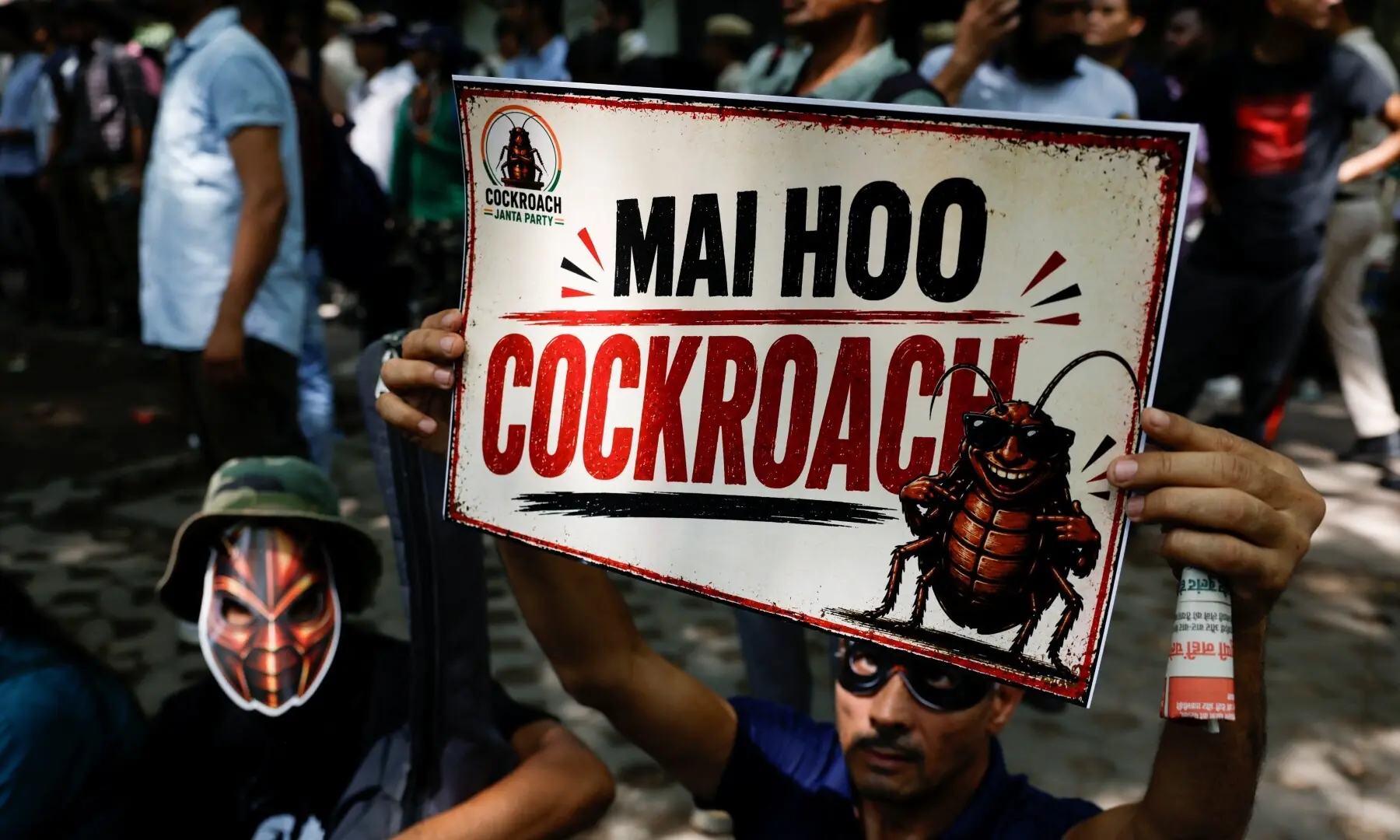 A person wearing a mask holds a poster which reads “I am a Cockroach”, as supporters of the Cockroach Janta Party (CJP) await the arrival of Abhijeet Dipke, head of the CJP, on the day of a sit-in protest demanding the resignation of Indian Education Minister Dharmendra Pradhan, in New Delhi, India on June 6, 2026. —Reuters