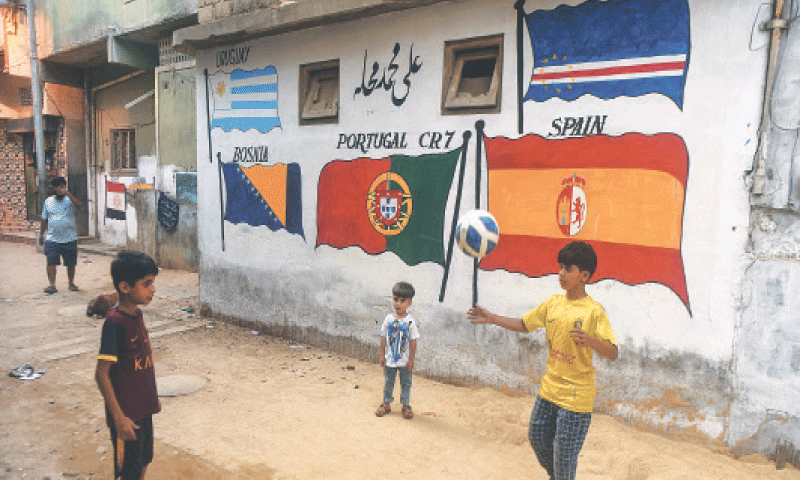 Against a wall painted with flags of competing nations, a boy juggles a football in a narrow alley of Lyari.—Fahim Siddiqi/ White Star Against a wall painted with flags of competing nations, a boy juggles a football in a narrow alley of Lyari.—Fahim Siddiqi/ White Star