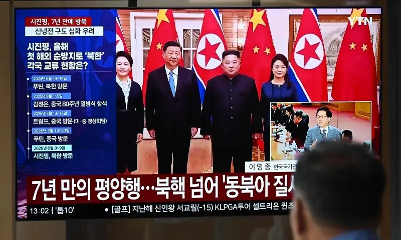 A man watches a television screen showing a news broadcast with file footage of the 2019 meeting between China's President Xi Jinping and North Korean leader Kim Jong Un, at a train station in Seoul on June 8, 2026. &mdash; AFP