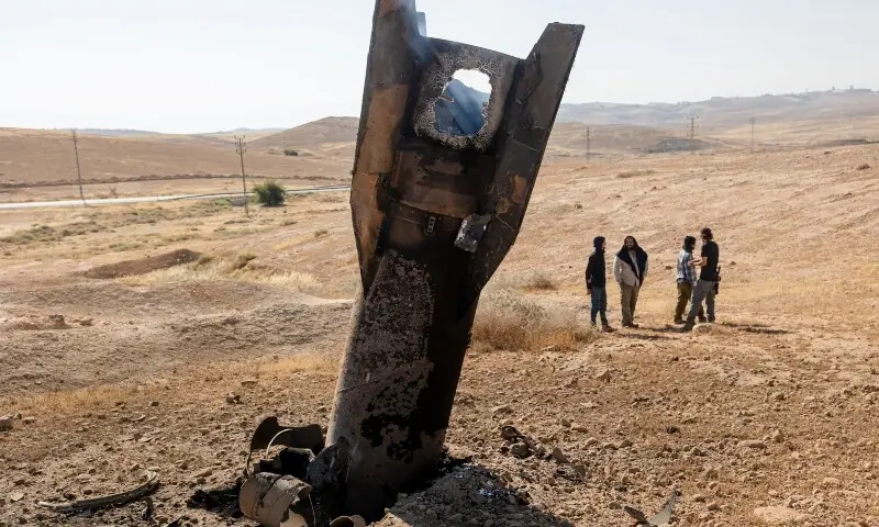 Israeli settlers stand next to part of a missile protruding from the ground, following strikes from Iran, in the central Israeli-occupied West Bank, June 8, 2026. &mdash;Reuters