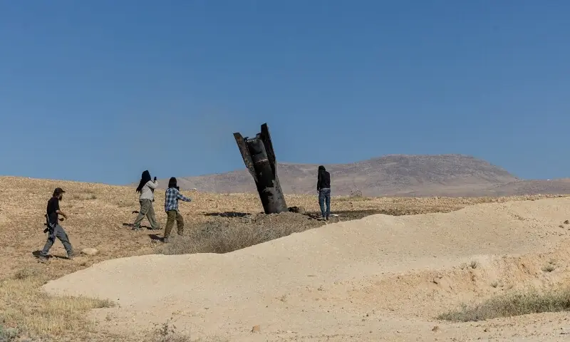 Israeli settlers stand next to part of a missile protruding from the ground, following strikes from Iran, in the central Israeli-occupied West Bank, June 8, 2026. &mdash;Reuters