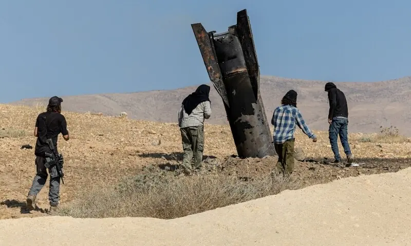 Israeli settlers stand next to part of a missile protruding from the ground, following strikes from Iran, in the central Israeli-occupied West Bank, June 8, 2026. &mdash;Reuters