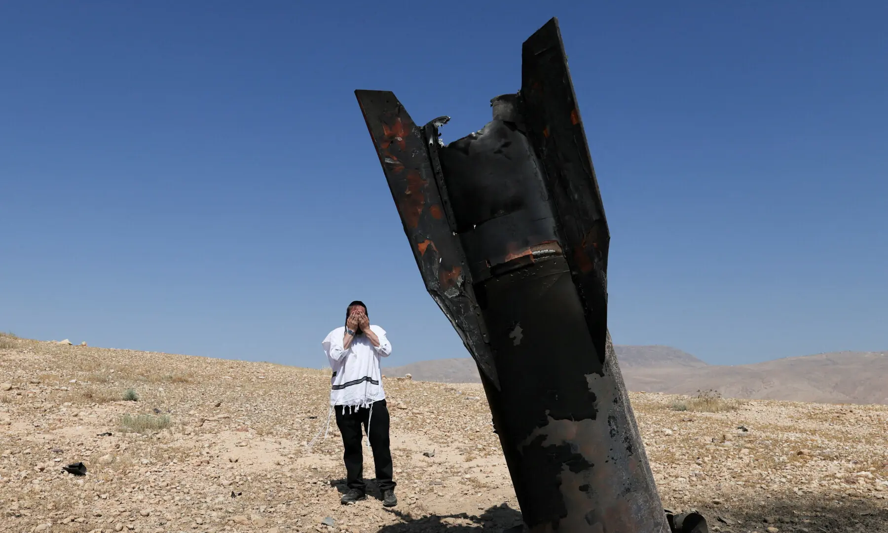  An Israeli ultra-Orthodox Jewish man reacts near a part of a missile protruding from the ground, following strikes from Iran, in the central Israeli-occupied West Bank on June 8, 2026. &mdash; Reuters 