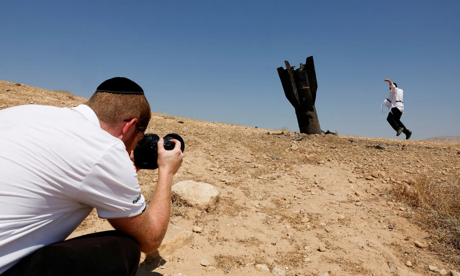  A person takes a photo of an Israeli ultra-Orthodox Jewish man reacting near a part of a missile protruding from the ground, following strikes from Iran, in the central Israeli-occupied West Bank on June 8, 2026. &mdash; AFP 