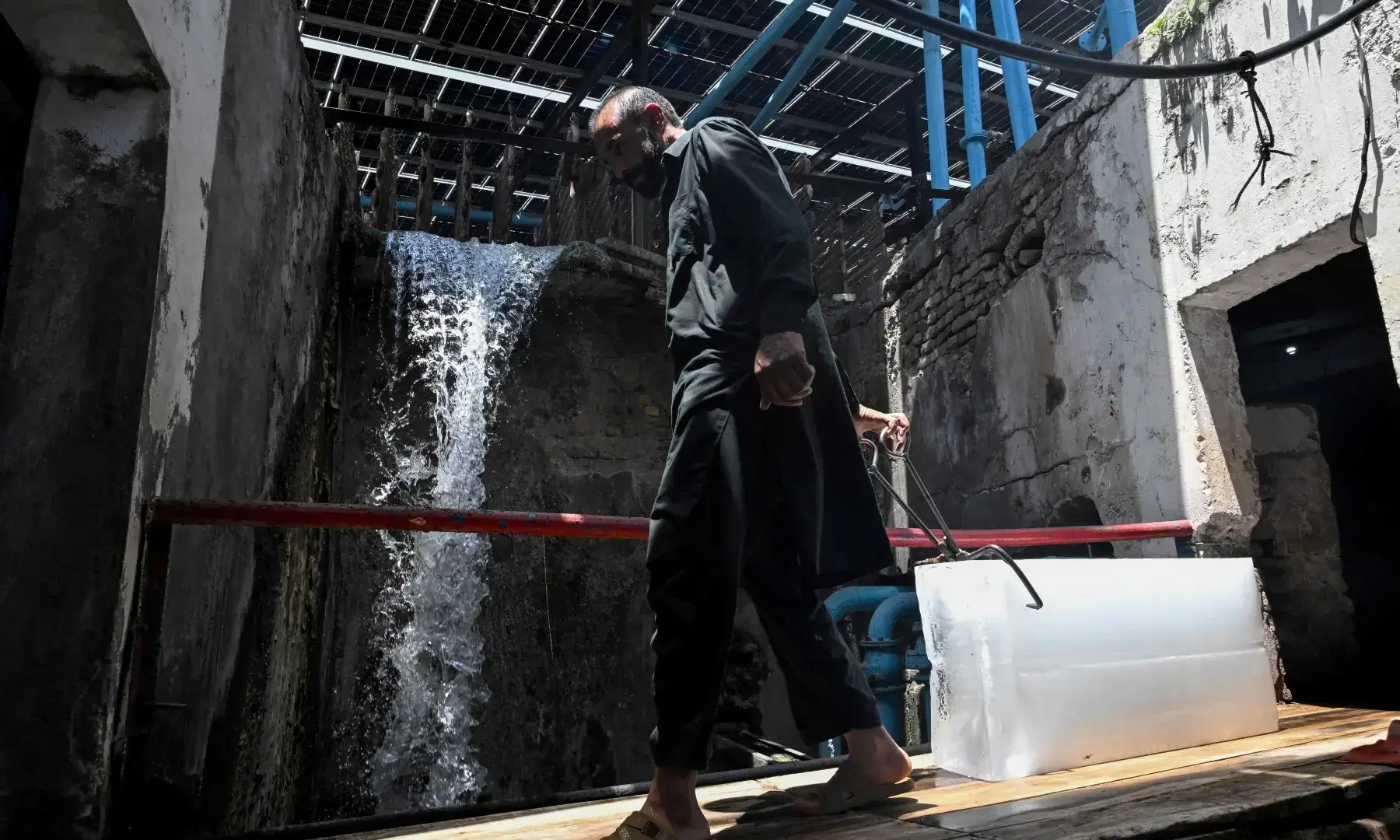 A worker pulls an ice block to load onto a vehicle at an ice factory amid a heatwave in Rawalpindi on June 9, 2026. &mdash;AFP