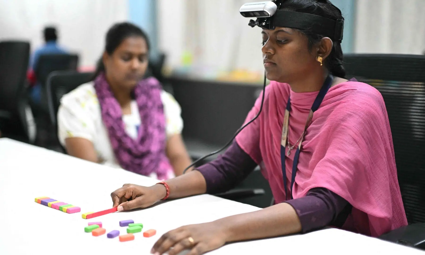 This photograph taken on May 13, 2026 shows a worker (R) wearing a RGB camera on her head recording actions through motion capture while arranging colored blocks at AI data company Objectways’ office in Tamil Nadu’s Karur district. — AFP