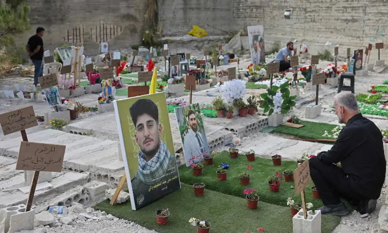 Hussein Tufayli (R) mourns over the grave of his son Mohammed Tufayli, a Hezbollah fighter who was killed during the ongoing war, at a temporary cemetery in the southern coastal Lebanese city of Sidon on June 11, 2026. &mdash; AFP