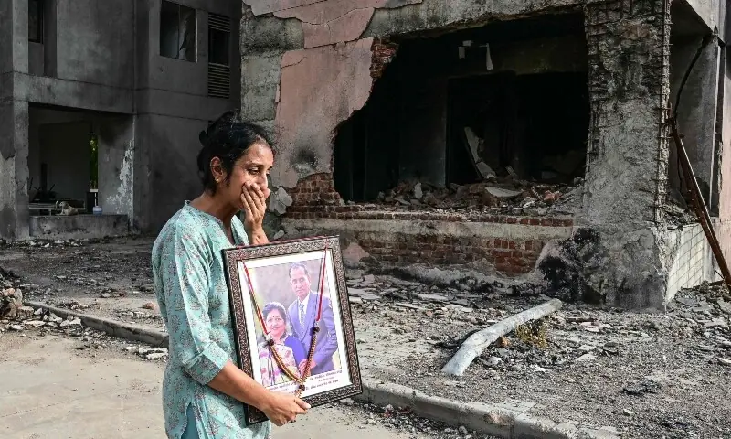 A woman holding a portrait of her relatives, who died in the Air India Flight 171 crash last year, breaks down while visiting the accident site in Ahmedabad on June 11. — AFP A woman holding a portrait of her relatives, who died in the Air India Flight 171 crash last year, breaks down while visiting the accident site in Ahmedabad on June 11. — AFP