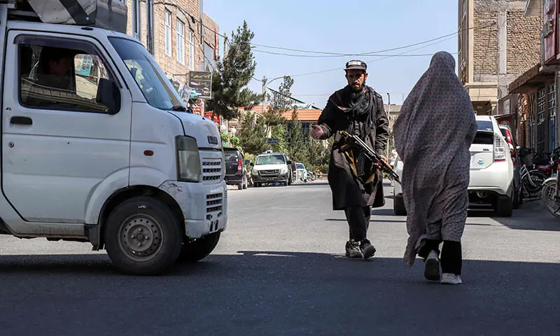 A burqa-clad woman walks past a Taliban security personnel standing guard outside a mosque in Herat.—AFP A burqa-clad woman walks past a Taliban security personnel standing guard outside a mosque in Herat.—AFP