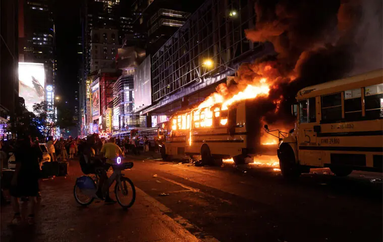REVELLERS and fans celebrating the New York Knicks’ win over the San Antonio Spurs and World Cup festivities watch as a bus catches fire in New York.—Reuters REVELLERS and fans celebrating the New York Knicks’ win over the San Antonio Spurs and World Cup festivities watch as a bus catches fire in New York.—Reuters