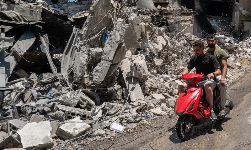  Men ride a motorcycle past shops and buildings damaged by Israeli strikes in Nabatieh, Lebanon, June 17, 2026. &mdash;Reuters 