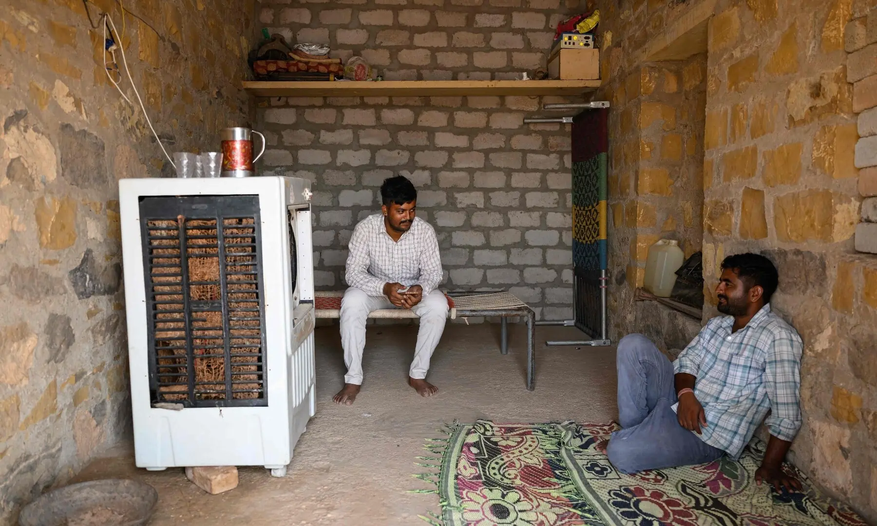 This photograph taken on May 29, 2026 shows herdsman Sawai Singh Bhati (L) talking to his brother while sitting in front of an air-cooler in 42 degrees Celsius temperatures, at his house in Sanwata village on the outskirts of Rajasthan’s Jaisalmer city. — AFP