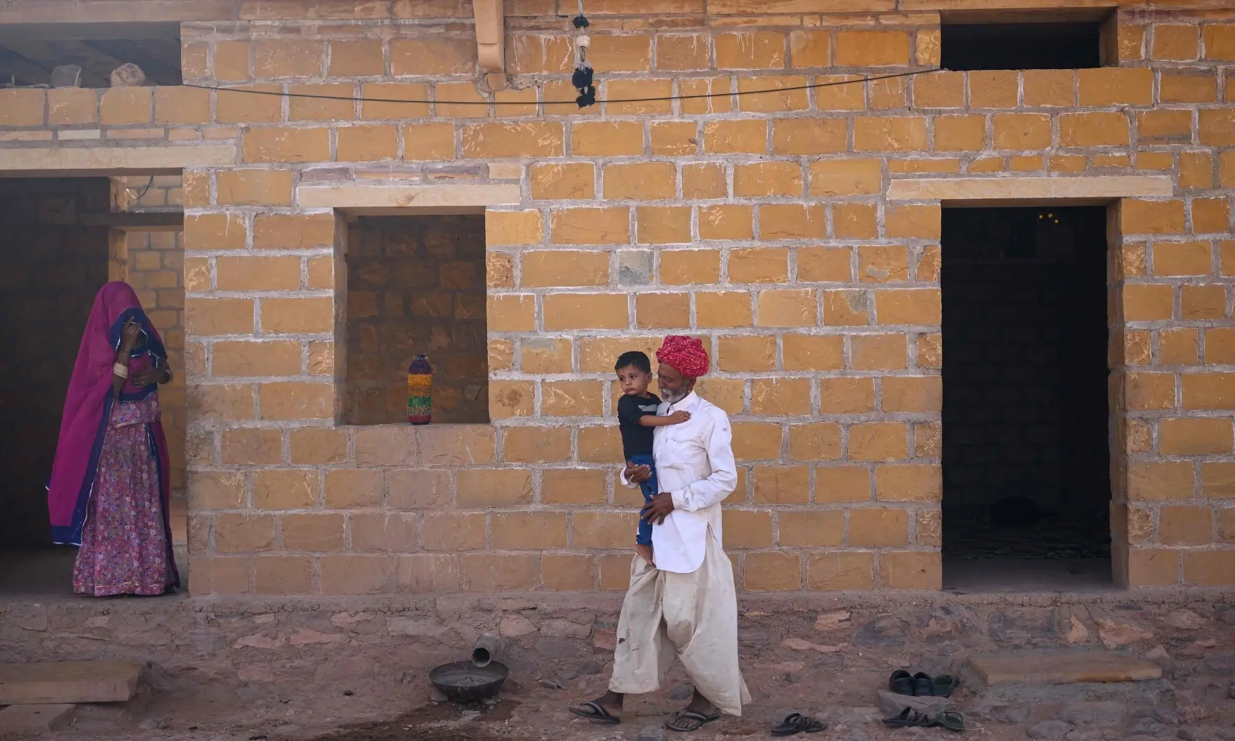 This photograph taken on May 29, 2026 shows herdsman Sawai Singh Bhati’s father, Khet Singh carrying his grandson at their house in Sanwata village on the outskirts of Rajasthan’s Jaisalmer city. — AFP