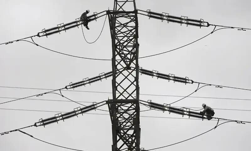 In this file photo technicians fix cables on a power transmission tower. — Reuters/File In this file photo technicians fix cables on a power transmission tower. — Reuters/File