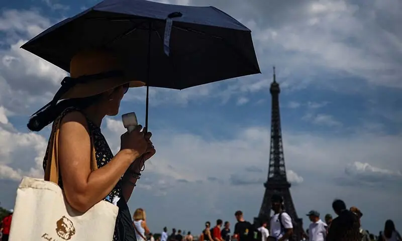 A woman protects herself from the sun under an umbrella on the Trocadero square near the Eiffel Tower as temperatures rise in Paris during a second heatwave affecting a large part of France, June 20, 2026. — Reuters