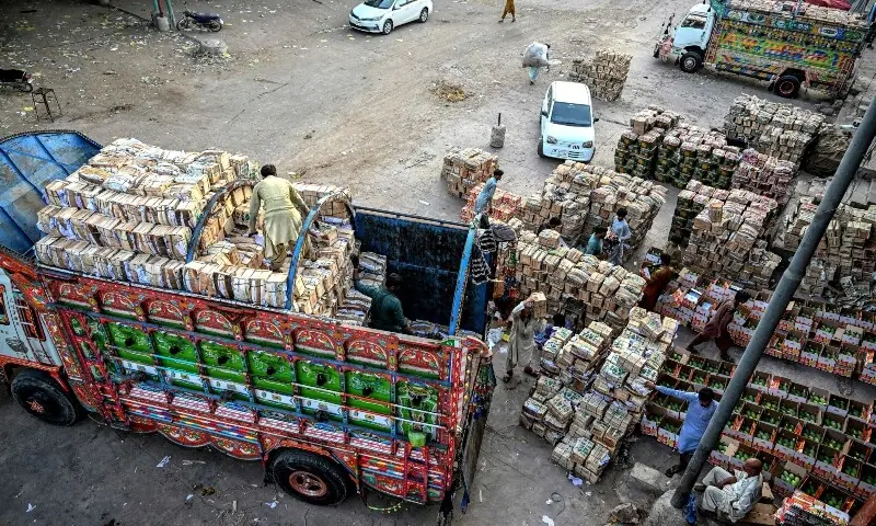 This photograph taken on June 5, 2026 shows workers loading boxes of mangoes onto a truck at a market in Karachi. — AFP