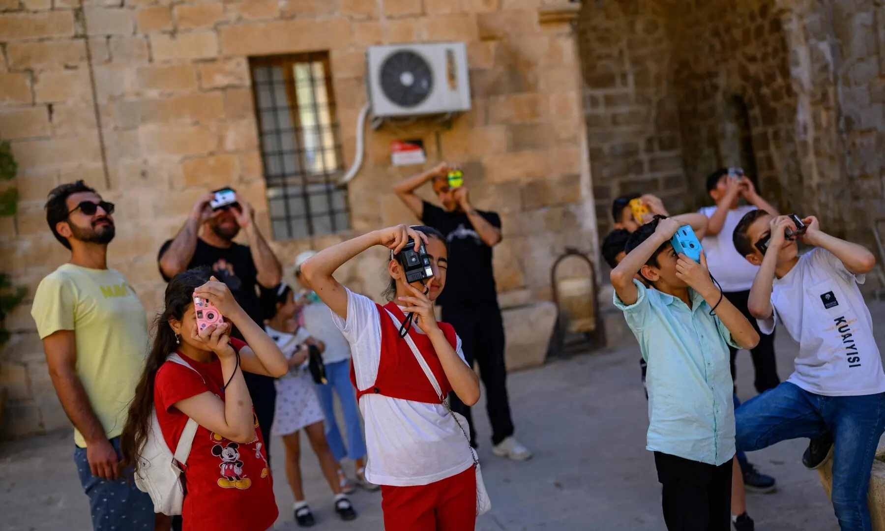 A group of children take pictures in the streets with their film cameras during a workshop held as part of Fotohane Darkroom project in Mardin, southeastern Turkiye, on June 14, 2026. — AFP