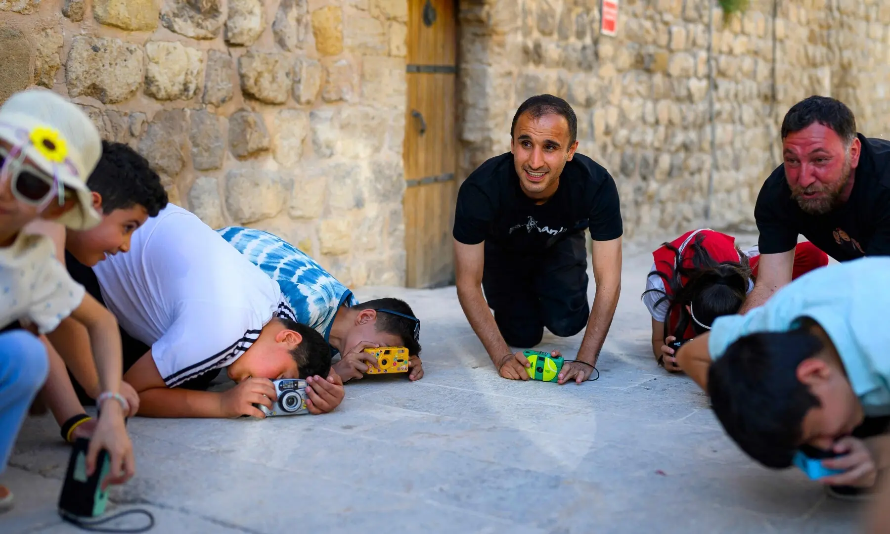 Syrian photographer, educator and co-founder of the project Serbest Salih (C) teaches children how to take pictures with film cameras in the streets during a workshop held as part of Fotohane Darkroom project in Mardin, southeastern Turkiye, on June 14, 2026. — AFP