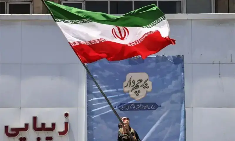 An Iranian woman waves a national flag at Tehran&rsquo;s Valiasr Square, after the United States and Iran agreed on a peace deal to end the over 100-day war.&mdash;AFP/File