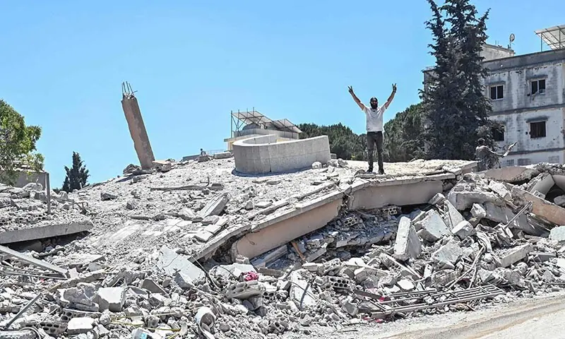 A resident flashes the V-sign for Victory as he stands on the roof of a collapsed home, destroyed in Israeli military strikes, in the southern Lebanese village of Srifa on June 24, 2026. — AFP