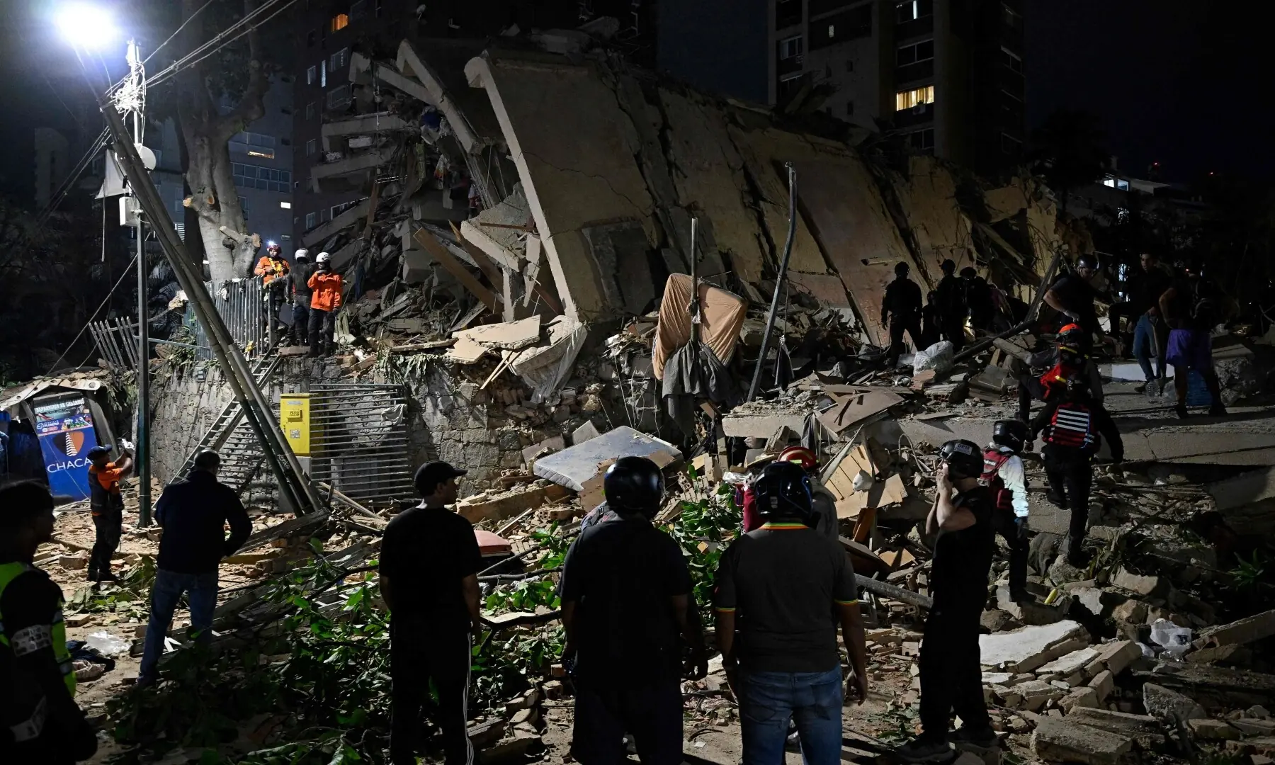  People gather on a street next to a damaged car and building following an earthquake in Valencia, Venezuela on June 24, 2026. &mdash;AFP 
