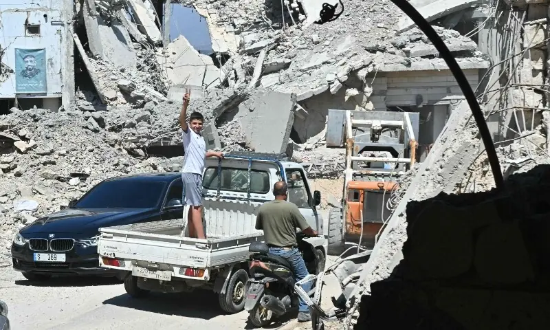 A Lebanese boy flashes the victory sign as he stands in the back of a truck driving past the rubble of destroyed homes and businesses following Israeli military strikes. in the southern Lebanese village of Srifa on June 24, 2026. &mdash;Reuters