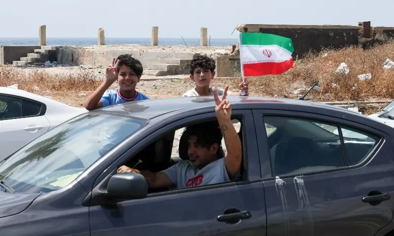  A boy waves an Iranian flag from a car as displaced people make their way back to their homes in southern Lebanon following an interim deal between the US and Iran, in Sidon, Lebanon, June 24, 2026. &mdash;Reuters 