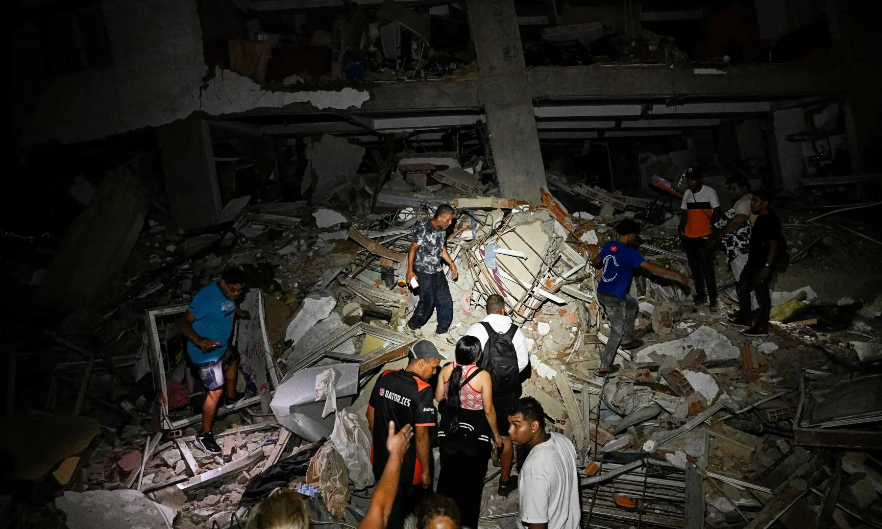 People walk in the rubble near a damaged building following an earthquake in Catia La Mar, La Guaira State, some 30kms north-west of Caracas, early on June 25, 2026. &mdash;AFP