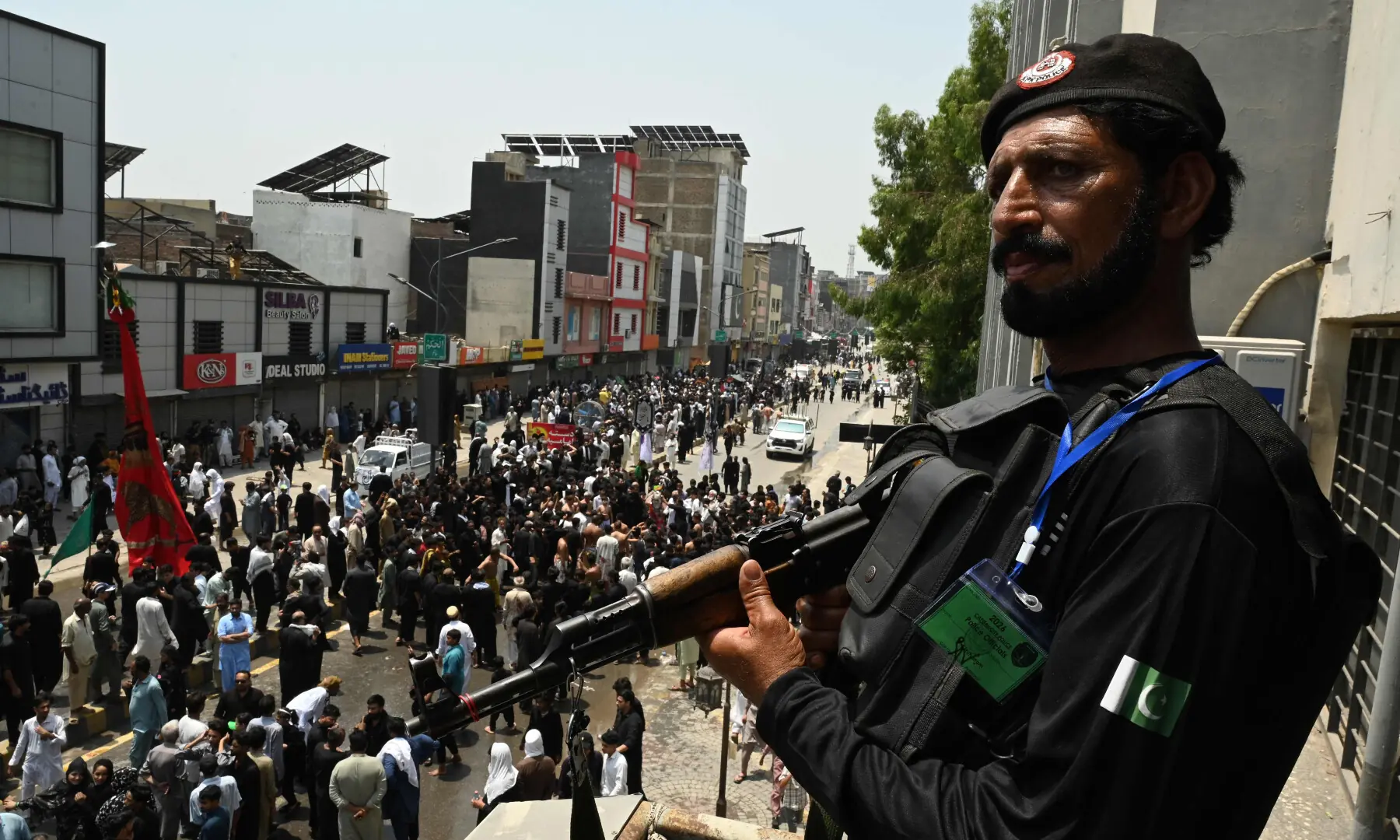 A security personnel stands guard as Muslims participate in a Muharram procession on the ninth day of Ashura in Peshawar on June 25, 2026. &mdash; AFP