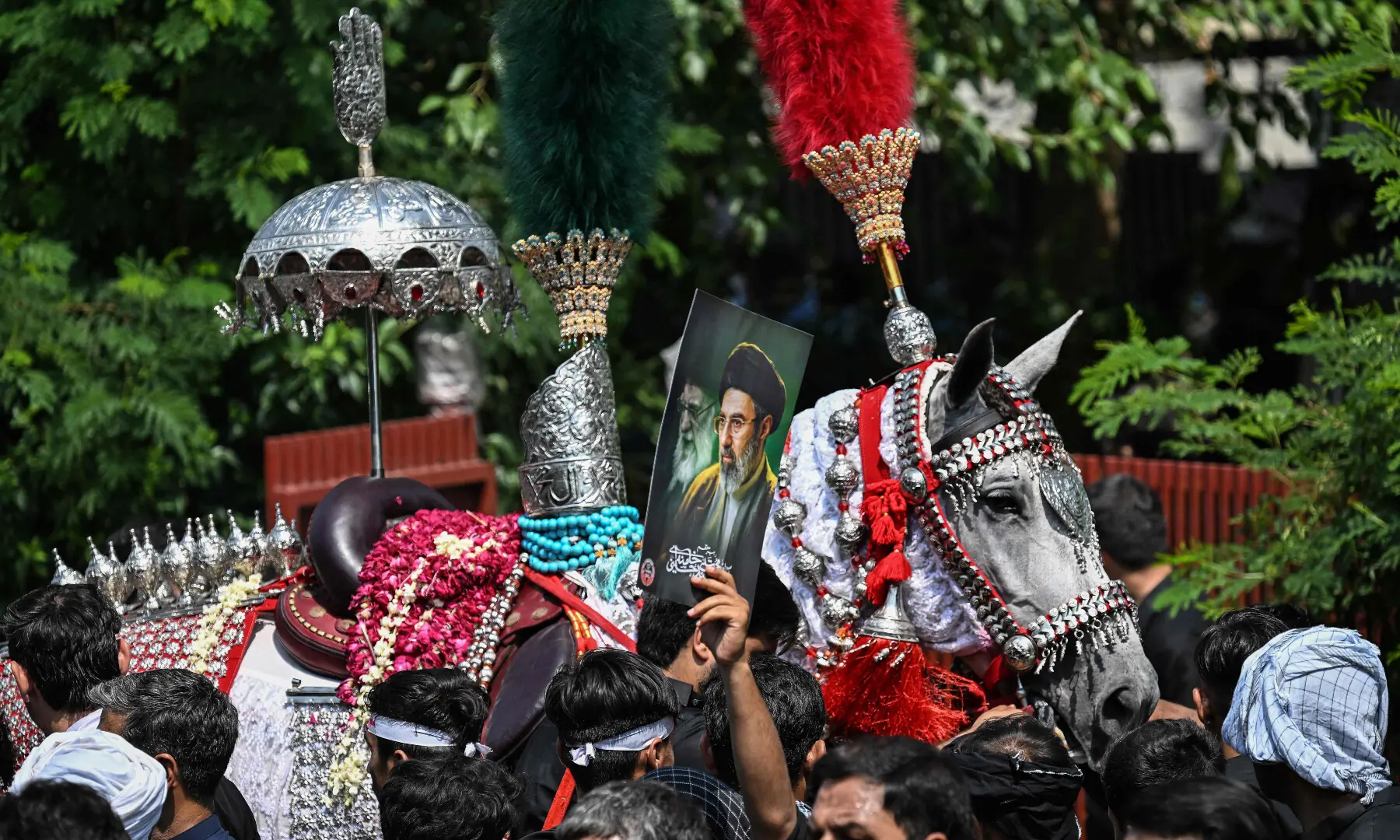 A person holds a poster with portraits of Iran&rsquo;s supreme leader Mojtaba Khamenei (R) and late supreme leader Ayatollah Ali Khamenei as mourners take part in a procession on the ninth day of Muharram in Islamabad on June 25, 2026. &mdash; AFP