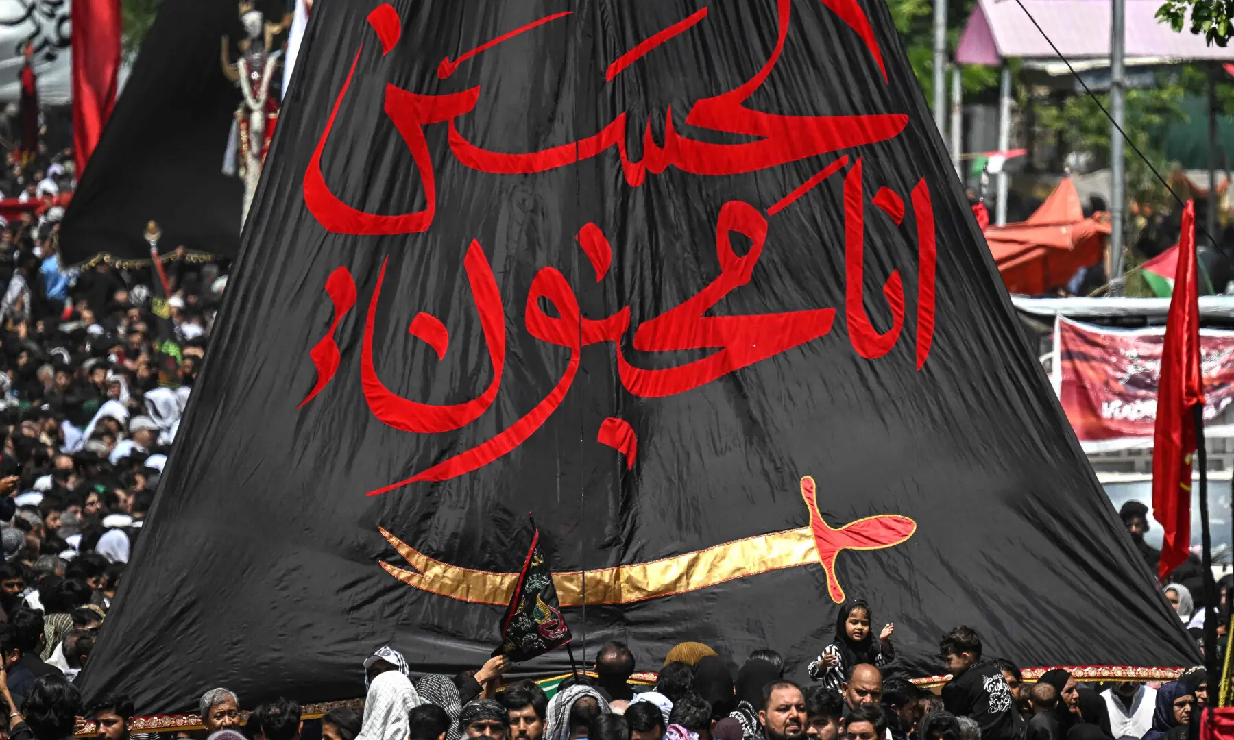 Muslims hold a religious flag as they take part in a procession on the ninth day of Muharram in Islamabad on June 25, 2026. &mdash; AFP