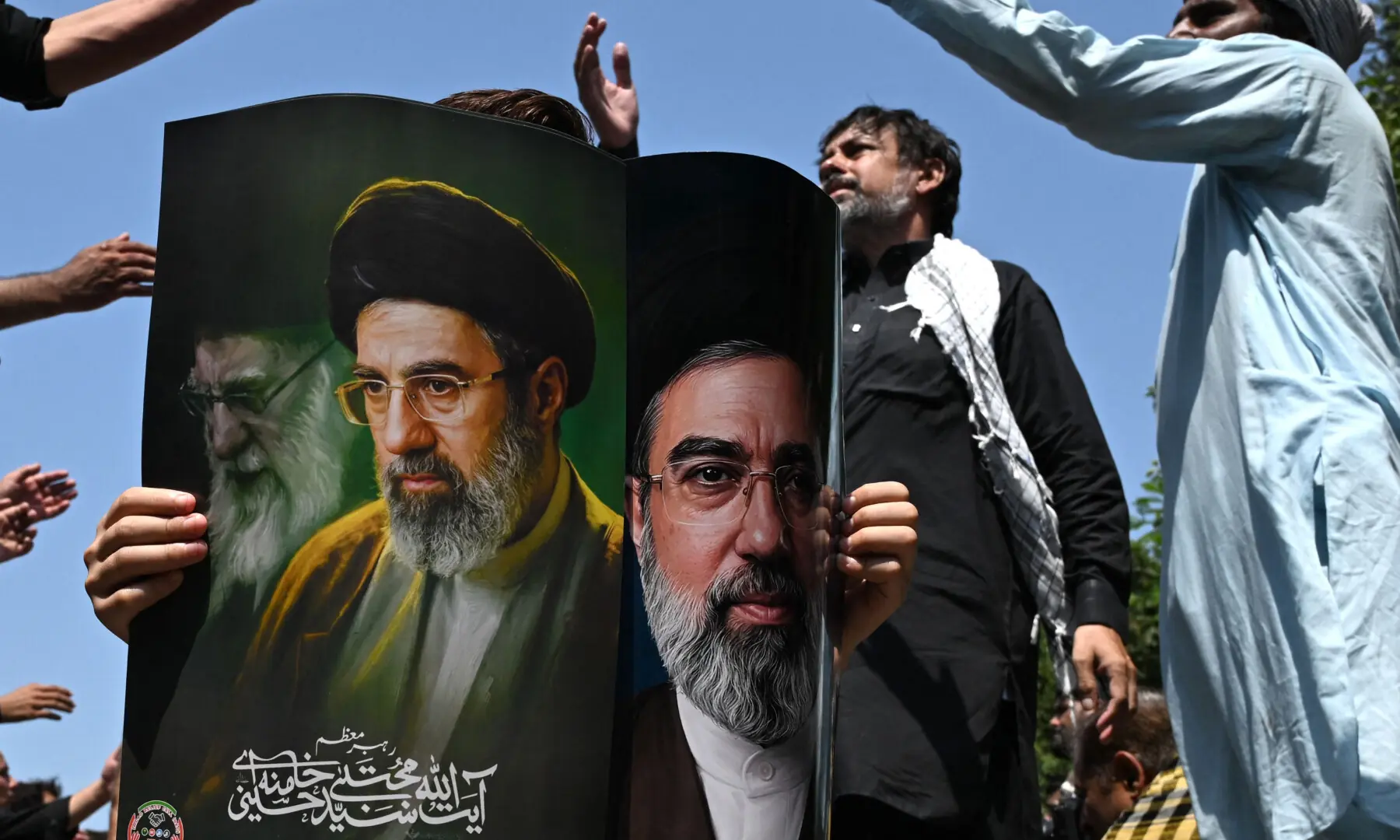 A person holds a poster with portraits of Iran&rsquo;s supreme leader Mojtaba Khamenei and late supreme leader Ayatollah Ali Khamenei (L) as mourners take part in a procession on the ninth day of Muharram in Islamabad on June 25, 2026. &mdash; AFP