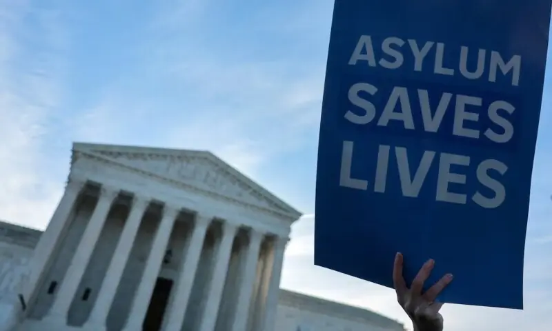 A demonstrator holds a sign as a small group of clergy gather for a vigil prior to arguments in Noem v Al Otro Lado, a case to determine if noncitizens blocked on the Mexican side of the border by US officials can apply for asylum, at the US Supreme Court building in Washington, DS, the US on March 24, 2026. &mdash; Reuters/File