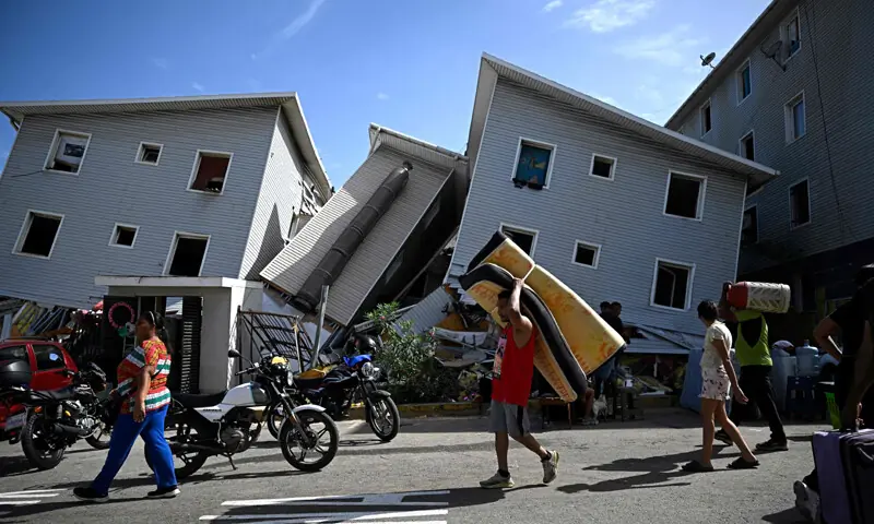 CARACAS: A man carries a mattress past damaged residential buildings in Catia La Mar, about 30km northwest of Caracas.&mdash;AFP