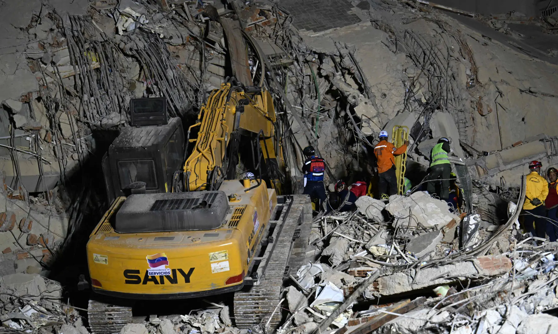 Rescue teams operate heavy machinery at the site of a collapsed building in Caracas on June 25, 2026, following earthquakes. &mdash; AFP