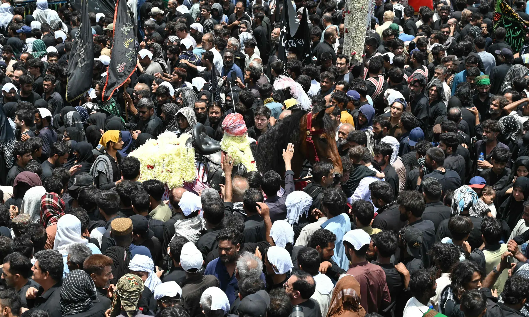 Mourners touch a horse symbolising the mount of Imam Hussain during a procession marking Ashura on the tenth day of Muharram in Karachi on June 26, 2026. &mdash; AFP