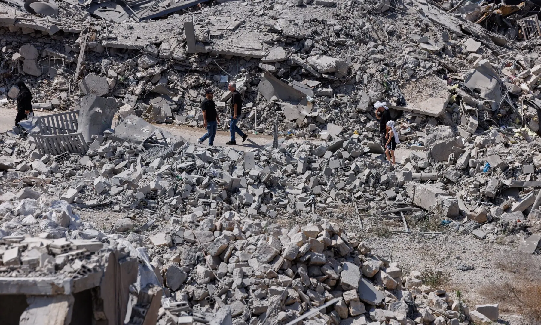People walk past buildings destroyed by an Israeli airstrike during the interim period following the US-Iran MoU, in Nabatieh, southern Lebanon on June 26, 2026. &mdash; Reuters
