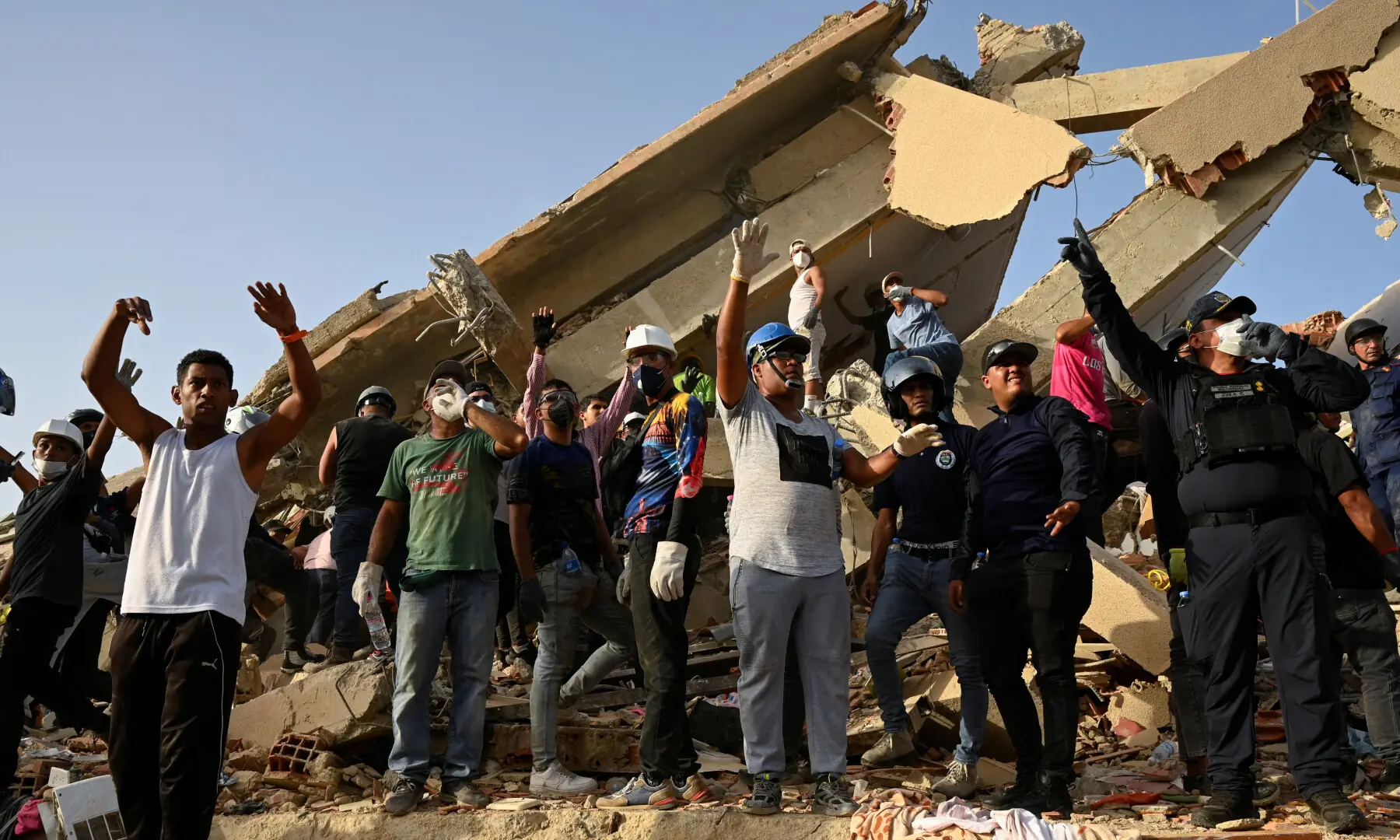 Rescuers raise their hands calling for silence in the streets to listen for victims buried in the rubble in the aftermath of earthquakes in La Guaira, Venezuela, on June 26, 2026. &mdash; Reuters